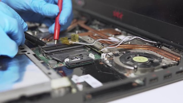 Moving close up view of old laptop diagnostics by a professional technician with special equipment and protective gloves.