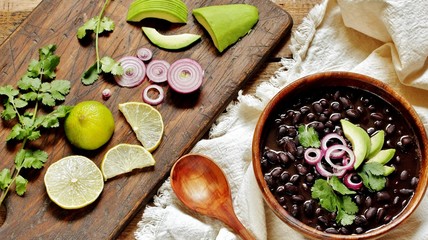 thick black bean soup or stew. Latin American or Mexican cuisine. stewed black beans served with avocado and red onion and cilantro. place for text. top view.
