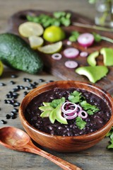 black bean soup or stew. Latin American or Mexican cuisine. stewed black beans served with avocado...