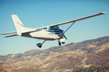 Rolgordijnen zonder boren Small single engine airplane flying in the gorgeous sunset sky through the sea of clouds above the spectacular mountains © Llstock