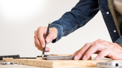Carpenter working carefully looking at the plans work in carpentry. He is successful entrepreneur at his workplace. hammering a nail Supports On Building Site work with cutter.