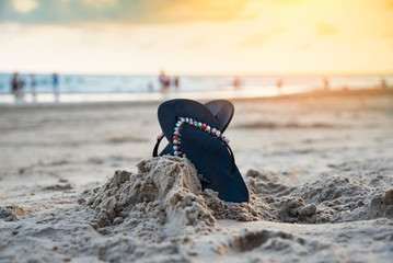 flip flops on beach with sandy beach sunset and ocean sea background