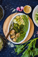 Baked roasted seasonal vegetables for vegan lunch or vegetarian dinner on table with mustard, spinach and fresh salad.