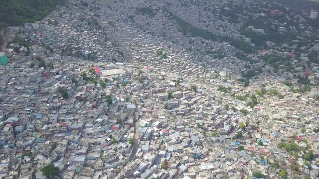 Amazing aerial over the slums, favela and shanty towns in the Cite Soleil district of Port Au Prince, Haiti with soccer stadium foreground.