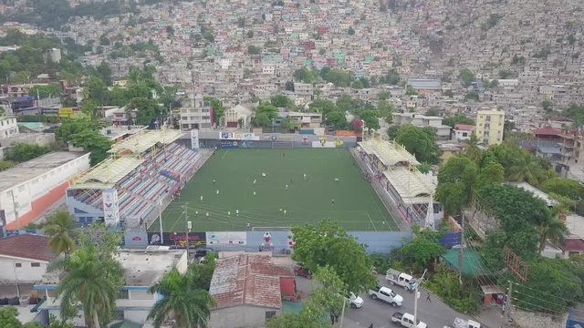 Aerial over the slums, favela and shanty towns in the Cite Soleil district of Port Au Prince, Haiti with soccer stadium foreground.