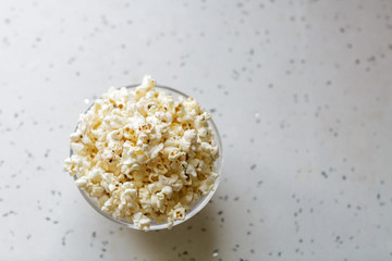 Fresh hot popcorn in glass bowl ready to be eaten. Flat lay, top view, copy space
