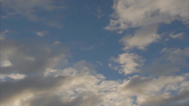 Time lapse clouds sail across a baby blue sky.