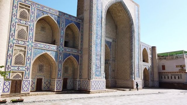 Abdulaziz-Khan madrasah in the morning light with a single tourist taking photos. In Bukhara, Uzbekistan.