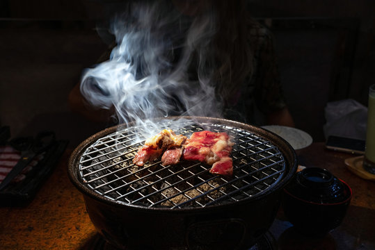 Cooked And Raw Beef On Charcoal Grill With Smoke