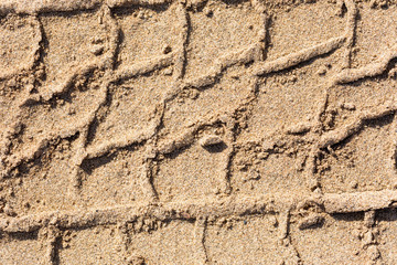 Print of a protector of tires of the car in crude sand on the river bank with various blades. Macro.