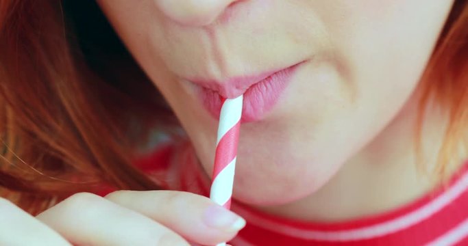 Closeup of girl mouth drinking from straw, green detox juice