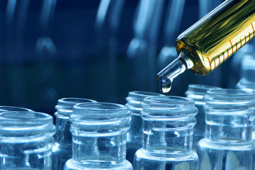 scientist using dropper sampling oil or chemical liquid drop to test tube with lab glassware in laboratory background, science or medical research and development concept 