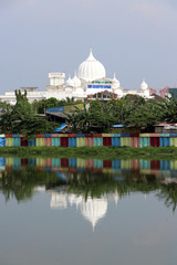White muslim mosque with green tree and colorful dam along the canal.