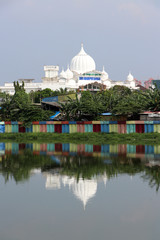 Obraz premium White muslim mosque with green tree and colorful dam along the canal.