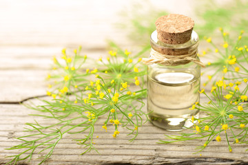 Fennel essential oil and fennel flowers on the wooden board