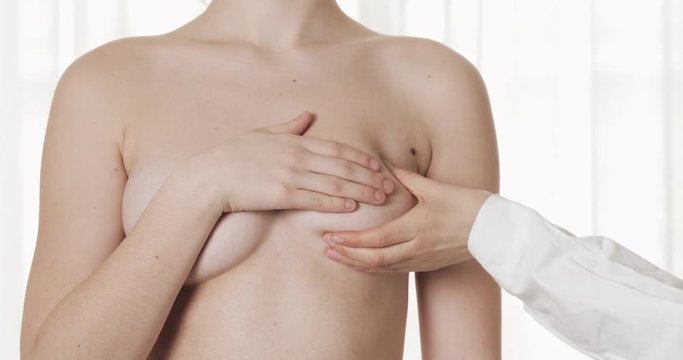 Doctor checking woman's breast at hospital. Breast Cancer Prevention. Close up.