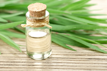 Tea tree essential oil in the galss bottle, on the wooden board