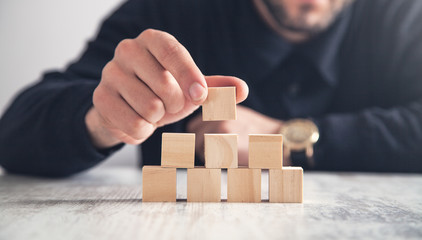 Man holding wooden cube on a office table.