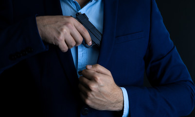 Man drawing his gun from coat pocket