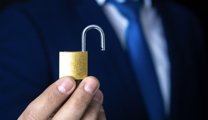 businessman holds open padlock in his hand