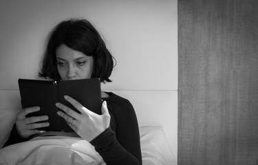 Black and white photo of woman reading an ebook