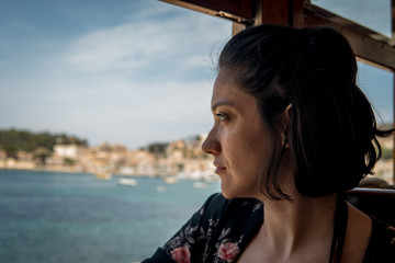 Young woman travelling alone on train. Beautiful view Port de Sóller in Mallorca island 