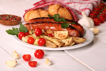 Grilled sausages with vegetables, spices and bread in white plate on white wooden table