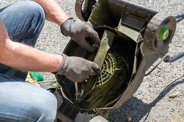 man repairing an electric lawn mower