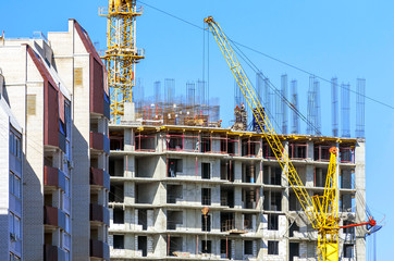 Finished Apartment Building and a New High-Rise Building Construction Site with Yellow Cranes against Blue Sky. Real Estate, Residential Buildings Urban Mixed-Use Development Concept.