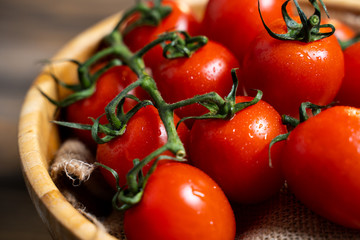 Fresh cherry tomatoes in a plate on a dark wood background.