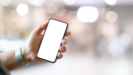 Man hand holding blank screen mobile smartphone over bokeh background