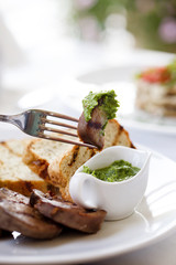 a piece of meat on a fork. Dinner in restaurant. Organic sauce and bread.