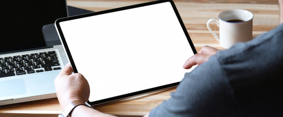 Closes up man holding tablet with isolate white screen on home office workspace