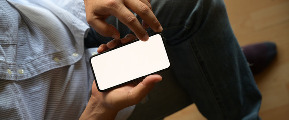 Top view man sitting and holding blank screen mock up mobile phone