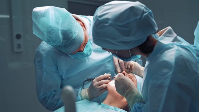 Doctor and assistent during operation. Dentist and a nurse treating a patient teeth