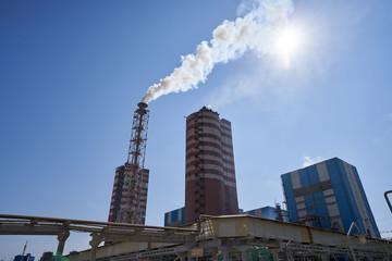 Fototapeta premium Large smoking chimney at a chemical fertilizer plant. Plant for the production of fertilizers against the blue sky