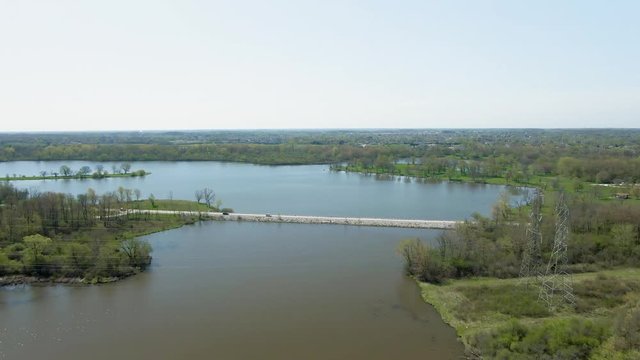 Aerial steady forward moving motion over a canal flowing into a small lake in a public park. Tampier Slough lake, Tampier Slough Woods. Western suburbs of Chicago, Illinois near Lemont.