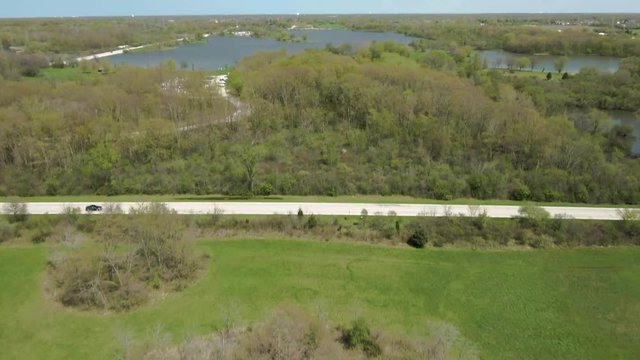 Aerial vertical reveal of public park in western suburbs of Chicago, Illinois. Tampier Slough lake, Tampier Slough Woods near Lemont, Illinois