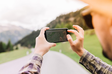 Male traveler spending time outside going to distant italian mountains and making itinerary. Close-up portrait of young man enjoying trip to Alps and looking at map in phone.