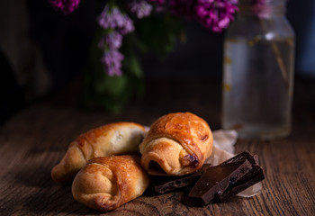 Rustic still life with a purple lilac, cakes and pieces of dark chocolate