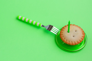 Candle in a cupcake for a holiday. The concept of a festive birthday card on green background