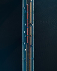 Bridge with two lanes and subway or train rails on a background of dark water. Aerial view