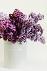 Obraz premium Purple bouquet of lilac flowers in a stylish vase on a white background