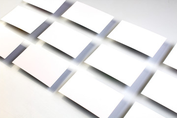 Mockup of horizontal business cards stacks arranged in rows at white textured paper background.