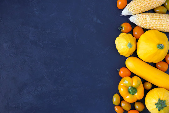 Assorted types of yellow vegetables on blue background. Top view with copy space