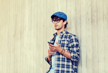people, music, technology, leisure and lifestyle - happy young hipster man with earphones and...