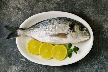Fresh raw dorado fish with lime slices and mint leaves. Top view.