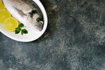 Fresh raw dorado fish with lime slices and mint leaves. Top view. Copy space. 