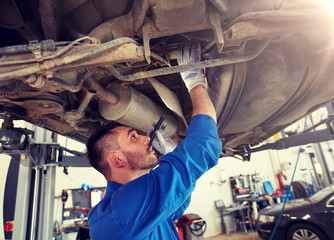 car service, repair, maintenance and people concept - auto mechanic man or smith with flashlight working at workshop