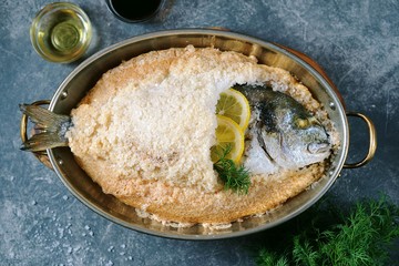 Sea fish, dorado fish baked in coarse salt mixed with egg white. Healthy food. Top view.